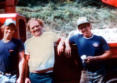 three men standing next to each other in front of a truck