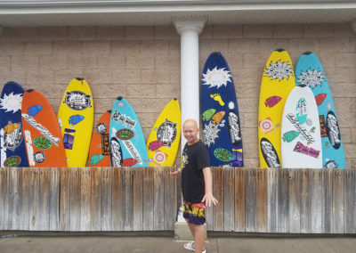 a man standing in front of a row of surfboards