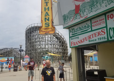 a man standing in front of a roller coaster