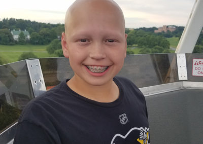 a young boy with a bald head smiles at the camera
