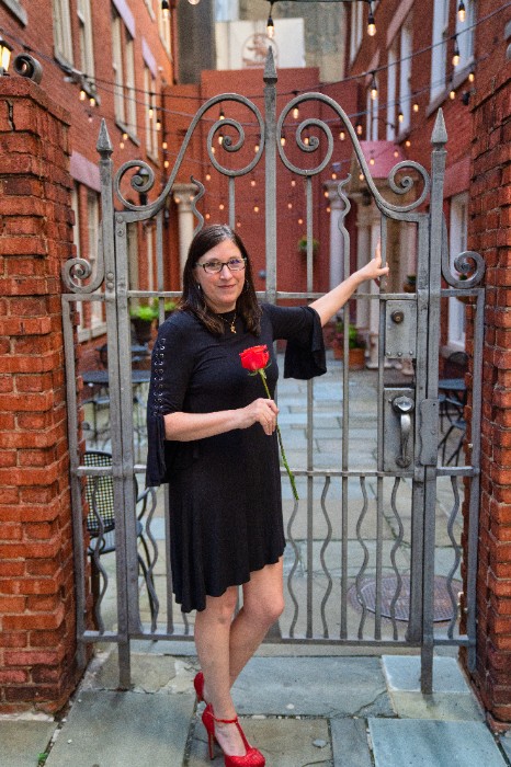 a woman standing in front of an iron gate