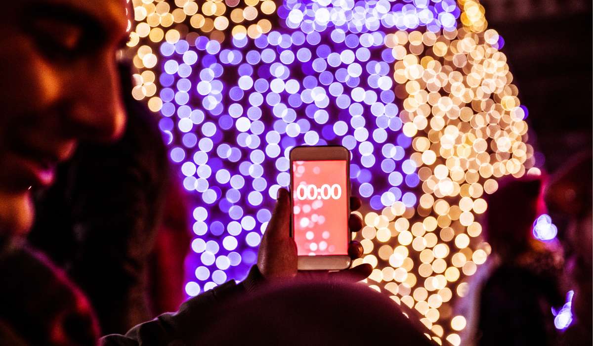 a person holding a cell phone in front of a christmas light display