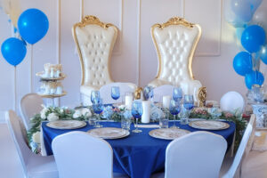 a table with blue and white decorations and balloons