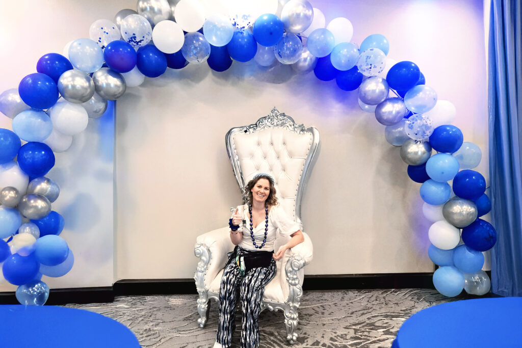 a woman sitting on a chair in front of a balloon arch